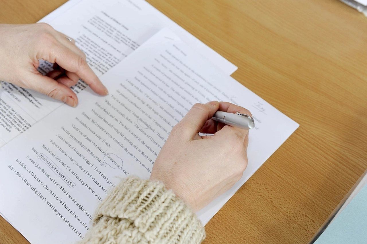 Hände prüfen ein ausgedrucktes Dokument mit einem Stift