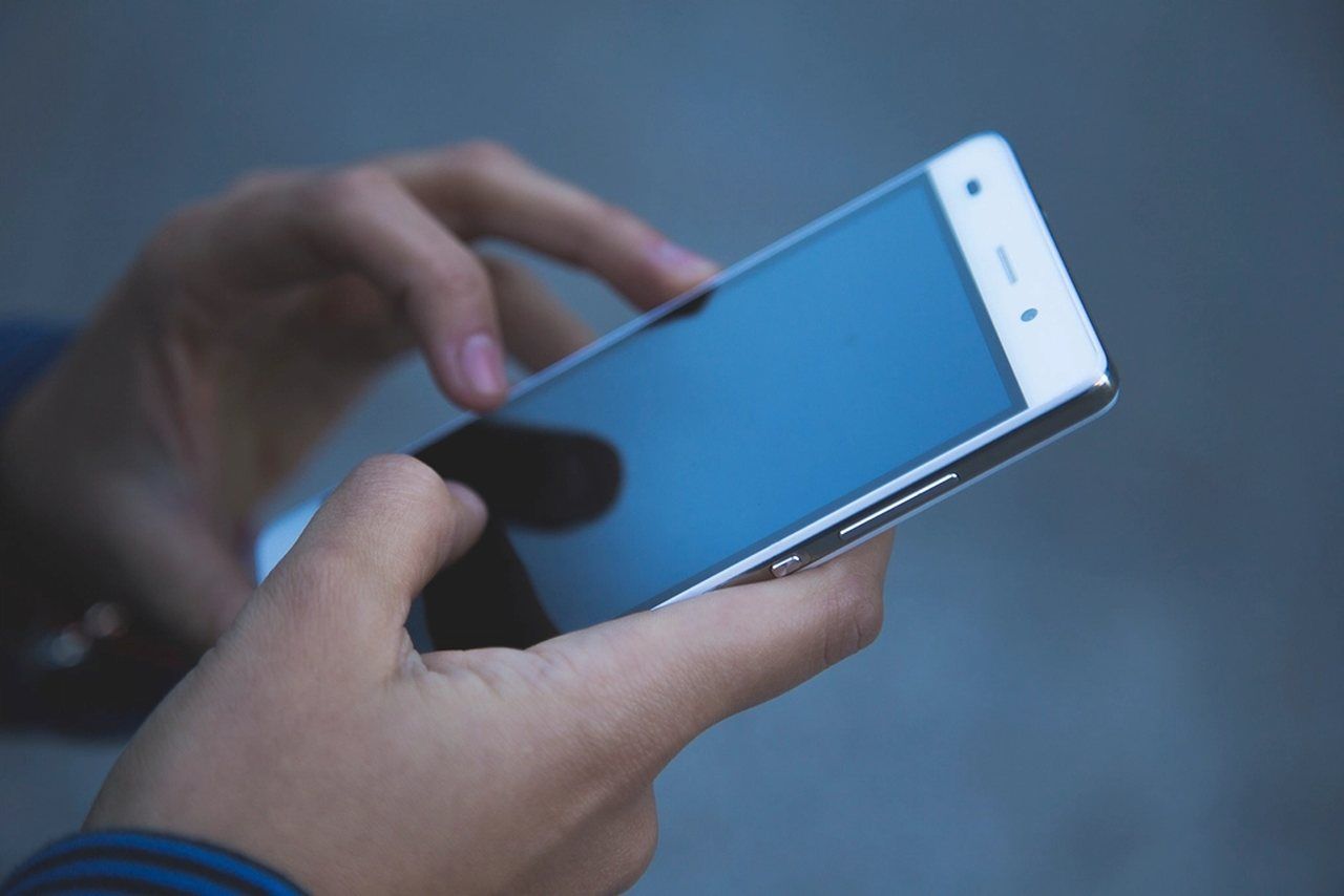 Hände halten ein Smartphone und tippen auf den Bildschirm