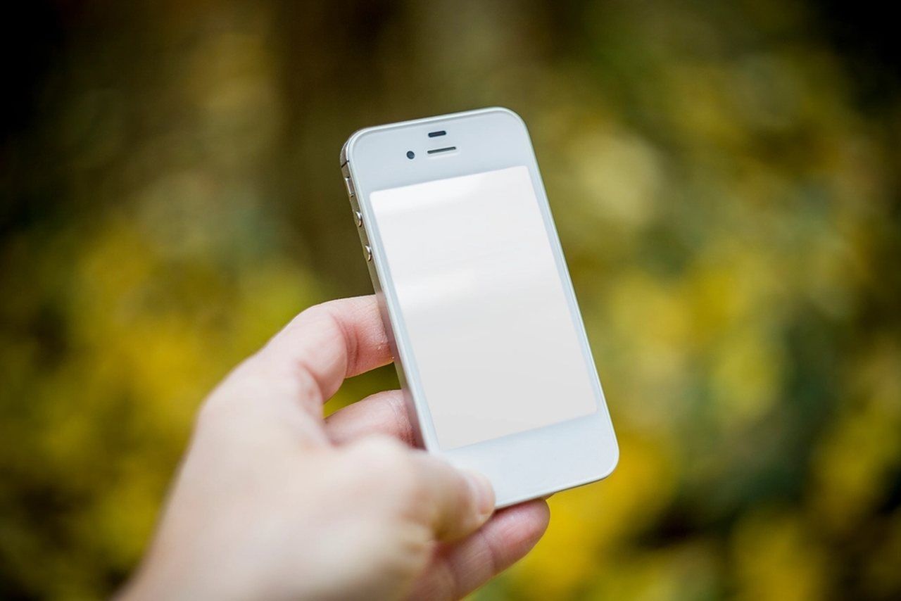 Hand hält ein Smartphone vor gelbem Hintergrund